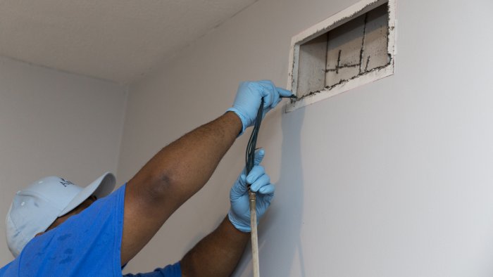 air duct cleaning technician cleaning air duct above his head